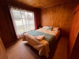 卡斯特鲁Hostal Magia Chilota的木制客房的一张床位,设有窗户