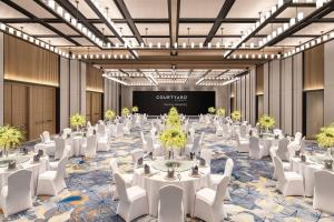 南京南京金轮万怡酒店的舞厅,配有桌子和白色椅子,投影屏幕