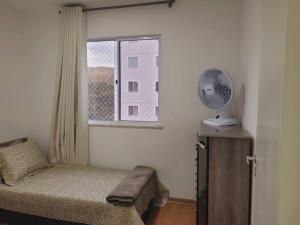 尤西德福拉Meu@Apê JF911 *Self-check-in*Elevador *Vaga grátis的一间卧室配有一张床和一个带风扇的窗户。