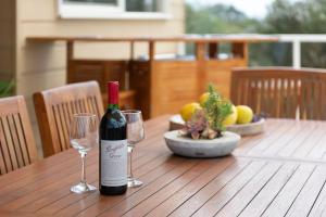 莱伊Ourania Luxury Villa with unforgettable sea views的木桌旁的一瓶葡萄酒和两杯酒
