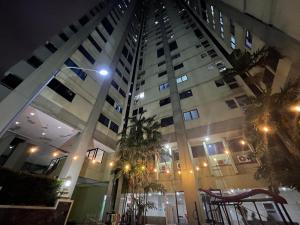 雅加达Highlander Apartemen Rajawali的一座高大的建筑,前面有棕榈树