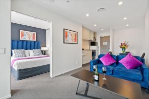 奥克兰曼努考/奥克兰机场近邻公寓的客厅配有蓝色的沙发和床。