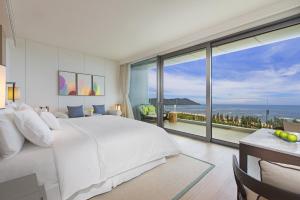 陵水海南蓝湾绿城威斯汀度假酒店（180°全海景客房）的卧室设有一张白色大床和大窗户