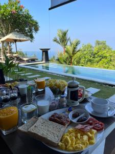 圣吉吉本哲龙目岛酒店的餐桌,在游泳池前的桌子上提供早餐食品