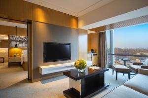 北京北京金茂万丽酒店的带电视的客厅和带沙发的客厅。