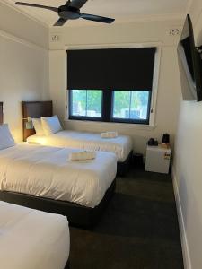 沃加沃加Sportsmens Club Hotel的一间卧室设有两张床和大窗户