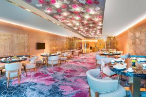 长沙长沙梅溪湖金茂豪华精选酒店的粉红色地毯上的带桌椅的用餐室