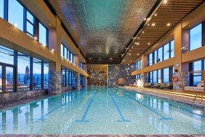 黄岛青岛西海岸威斯汀酒店的一座大型游泳池,位于一座带窗户的建筑内