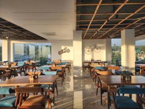 达兰萨拉Portola Hotel By Parkside的餐厅设有木桌和椅子以及大窗户。