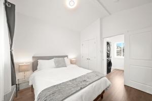 温哥华Entire NEW Cozy and Modern 2-storey HOUSE的白色的卧室设有一张大床和一个窗户