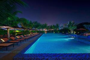 孟买孟买花园城威斯汀酒店的游泳池,晚上有椅子和棕榈树