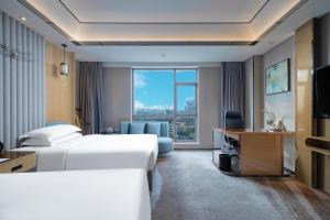 南昌南昌万怡酒店的酒店客房设有两张床、一张书桌和一个窗户。