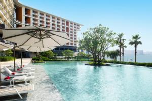 惠州惠州小径湾艾美酒店的酒店游泳池设有椅子和遮阳伞