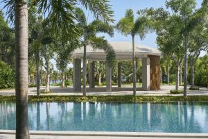 三亚三亚艾迪逊酒店的一个带凉亭和棕榈树的游泳池
