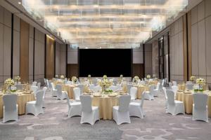 宝安深圳联投东方万怡酒店的一间会议室,配有桌子、白色椅子和屏幕