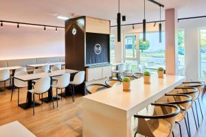 美因河畔法兰克福B&B Hotel Frankfurt-Airport的餐厅设有白色的桌椅和窗户。
