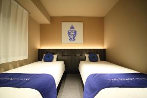 大阪Dynasty Hotel & Resort Osaka的配有蓝色枕头的客房内的两张床