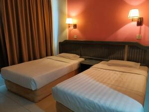 斗湖Monaco Hotel的红色墙壁的酒店客房内的两张床