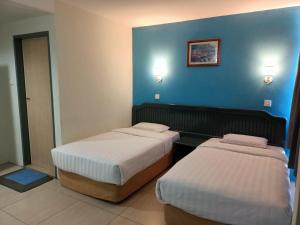 斗湖Monaco Hotel的两张位于酒店客房的床,拥有蓝色的墙壁