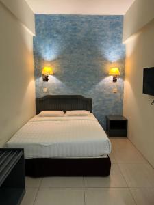 斗湖Monaco Hotel的一间卧室设有一张床和蓝色的墙壁