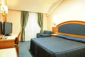 卡普拉罗拉Hotel La Bella Venere的配有一张床和一台平面电视的酒店客房
