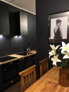 斯扎瓦诺泽德霍Słowackiego No. 5 APARTMENT的厨房配有黑色橱柜和白色花卉木桌