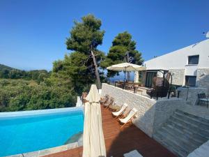 斯基亚索斯镇Allure Luxury Villas的一座房子旁的游泳池,配有躺椅和遮阳伞