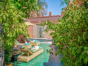马拉喀什Riad Dar Sido的一个带椅子的庭院和一个树木繁茂的游泳池