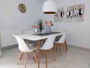 尼乌波特Duplex Villa Capricia appartement met zwembad Nieuwpoort Jachthaven的一间设有白色桌子和白色椅子的用餐室