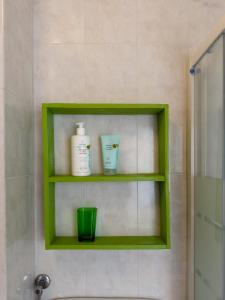 法尔科纳拉·玛里提马Host4All casa vacanze的浴室里绿着的架子,有两瓶和绿杯