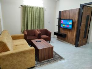班加罗尔Hotel Bulande Comforts-1 Bedroom Flat的客厅配有两把椅子和电视