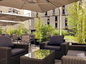 克莱蒙费朗克莱蒙费朗美居中心焦德广场酒店的庭院配有桌椅和遮阳伞。