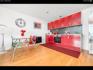 卡迪夫Stunning Spacious City Apartment with free parking的厨房配有红色橱柜、桌子和时钟