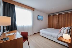 普拉亚达维多利亚Hotel Praia Marina by RIDAN Hotels的酒店客房配有一张床、一张书桌和一台电视。