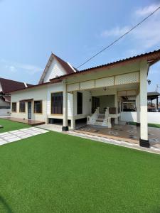 Kampong Bukit KatilTraditional Melaka Homestay with Private Pool的前面有绿色草坪的房子