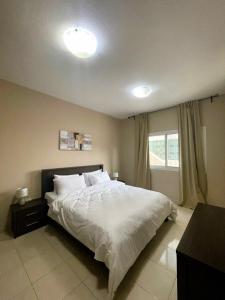 迪拜Marbella Holiday Homes - Al Nahda 2BHK的一间卧室配有一张带白色床单的床和一扇窗户。