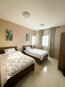 迪拜Marbella Holiday Homes - Al Nahda 2BHK的酒店客房设有两张床和窗户。
