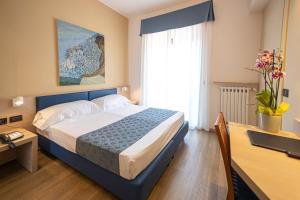 热那亚伊斯佩里亚酒店的一间卧室配有一张床、一张书桌和一个窗户。