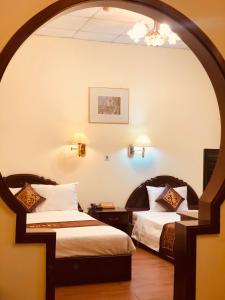 胡志明市Ngọc Lan Hotel的带拱门的酒店客房内的两张床