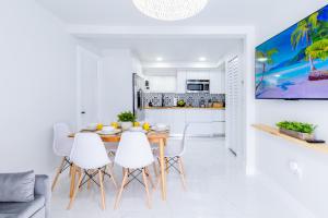 迈阿密Serenity Lodge Condo的白色的厨房和配有木桌及白色椅子的用餐室
