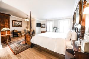 圣阿加瑟莫StoneHaven Le Manoir - Relais & Châteaux的卧室配有一张白色大床和一张书桌