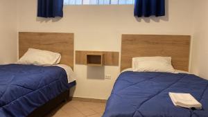 卡哈马卡La Pascana Hospedaje的一间卧室设有两张带蓝色床单的床和窗户。