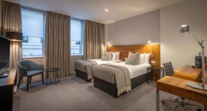 伦敦Clayton Hotel London Wall的酒店客房配有两张床和一张书桌