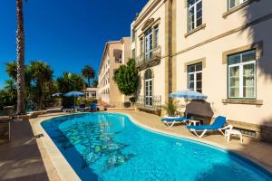 维迪堡索尔及塞拉酒店的一座带椅子和遮阳伞的游泳池位于一座建筑旁边