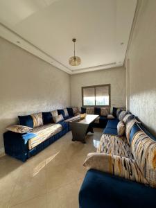 布兹尼盖Apparemment de luxe Bouznika的大型客厅配有蓝色的沙发和桌子