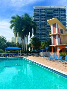 好莱坞Bposhtels Hollywood Florida的一座带椅子和棕榈树的游泳池以及一座建筑
