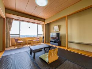 加贺LiVEMAX RESORT Kaga Yamashiro的客厅配有桌椅和电视。