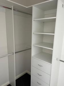 墨尔本ABC Homes的步入式衣柜,配有白色橱柜和抽屉