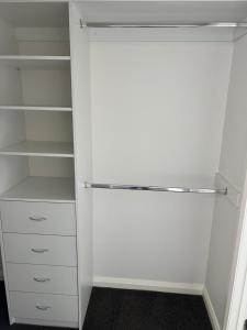 墨尔本ABC Homes的白色衣柜,配有白色架子和白色橱柜
