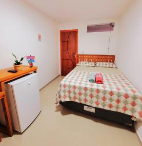 伊塔卡雷Praieira Hostel&Pousada的一间卧室配有一张床、一张书桌和一台冰箱